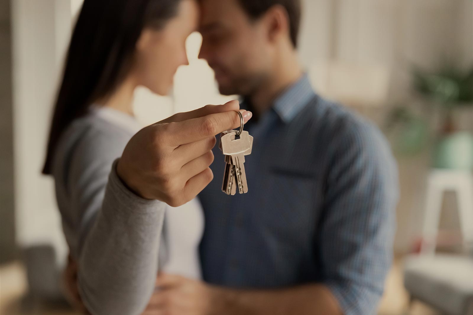 ein junges Paar hält die Schlüssel der neuen Wohnung in der Hand 